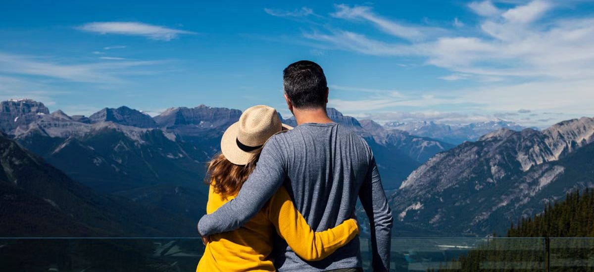 A couple embraces while enjoying a breathtaking view of the mountains in Banff, Alberta.