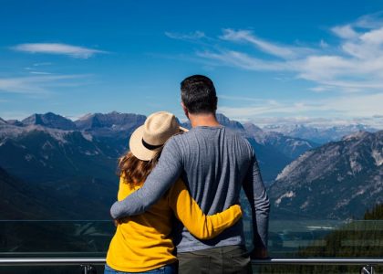 A couple embraces while enjoying a breathtaking view of the mountains in Banff, Alberta.